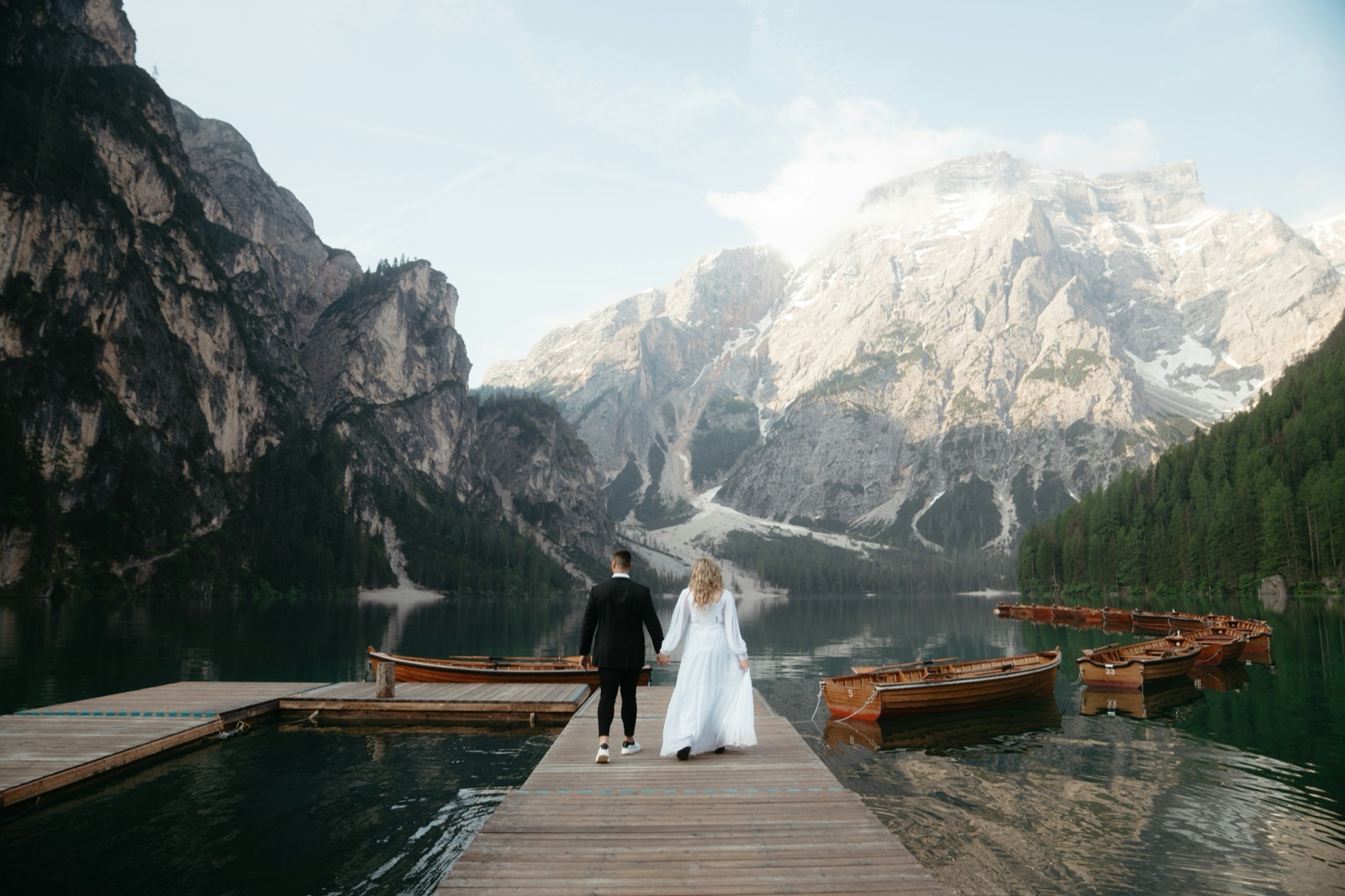 A wedding couple on a wooden dock beneath the Dolomites at Lago di Braies.