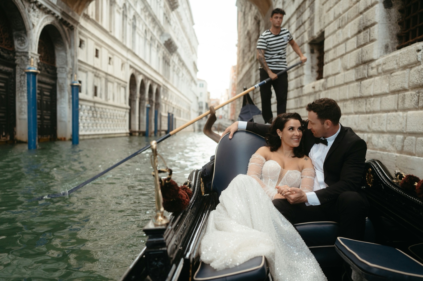A newlywed couple enjoying a gondola ride through Venice.