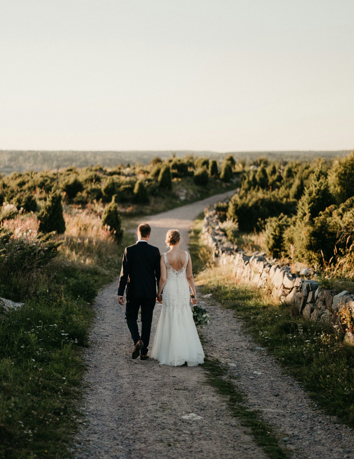 A bride and groom walking along a country road in Tuscany at sunset.