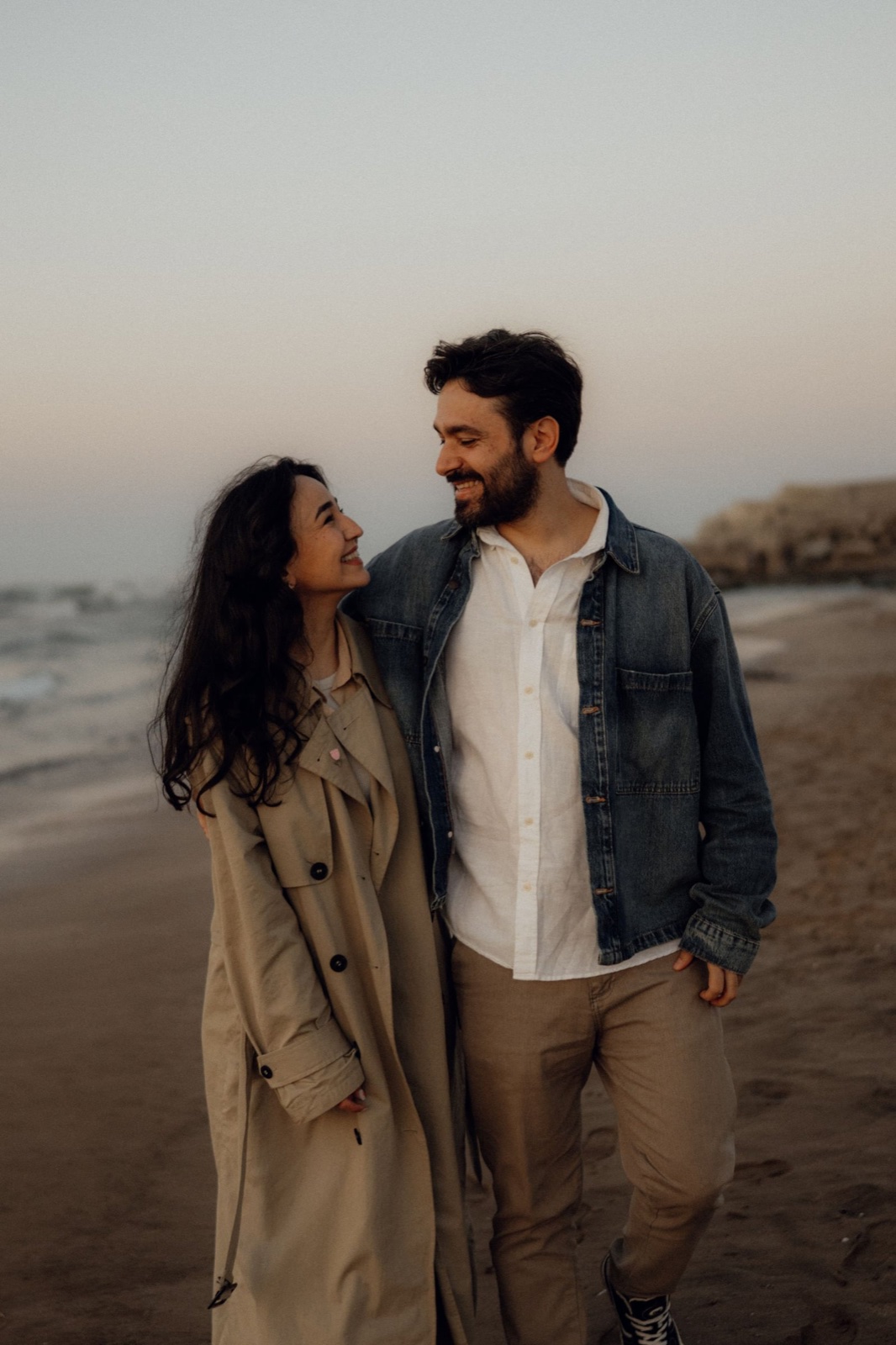 A smiling couple sharing a quiet moment on the beach at sunset.
