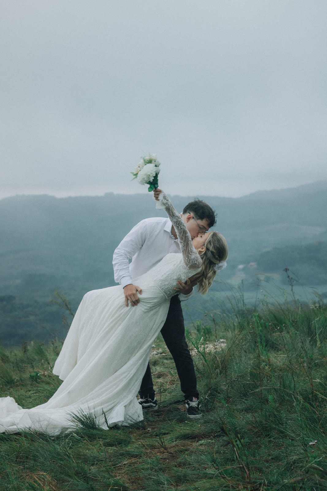 A wedding couple embracing in an open mountain landscape